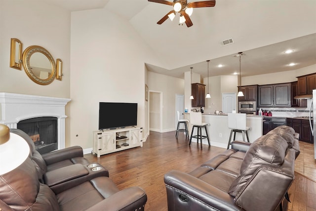 living room featuring ceiling fan, high vaulted ceiling, and dark hardwood / wood-style flooring