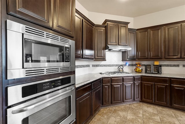 kitchen with decorative backsplash, dark brown cabinetry, stainless steel appliances, and light tile patterned floors