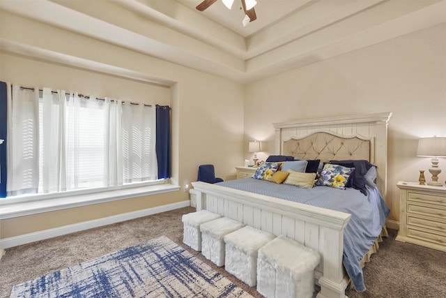 carpeted bedroom with ceiling fan and a raised ceiling