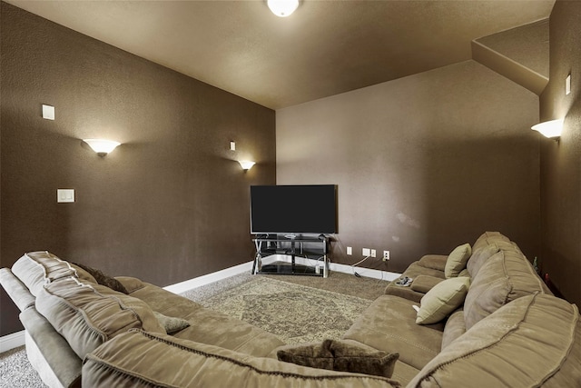 carpeted cinema room with vaulted ceiling