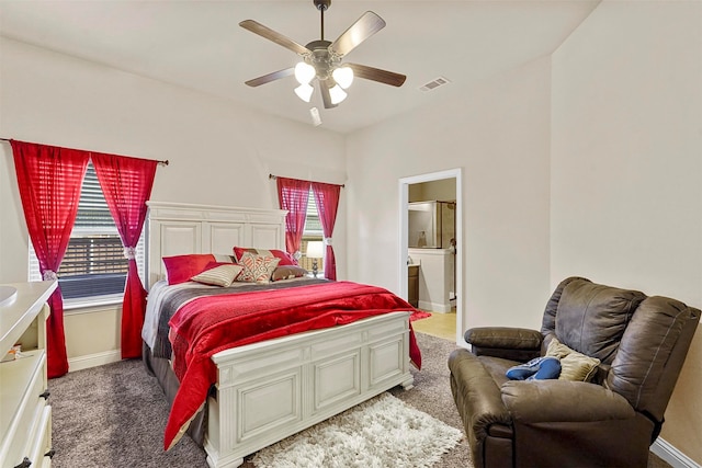 bedroom featuring ensuite bath, dark colored carpet, and ceiling fan