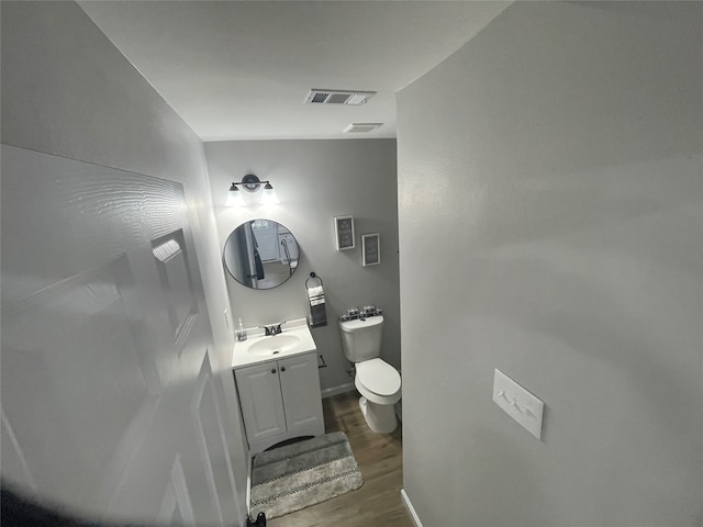 bathroom with hardwood / wood-style flooring, vanity, and toilet