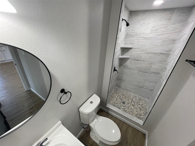 bathroom with hardwood / wood-style floors, tiled shower, vanity, and toilet