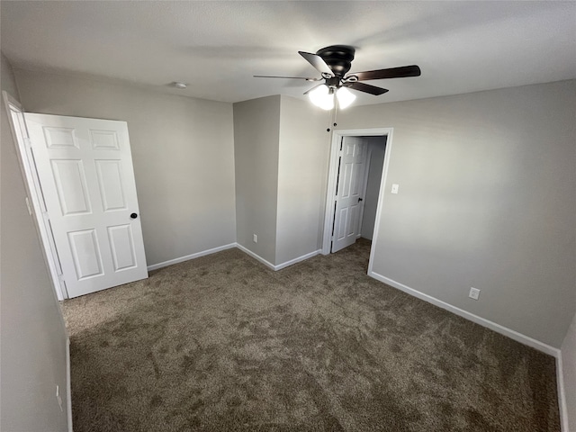 spare room featuring dark colored carpet and ceiling fan