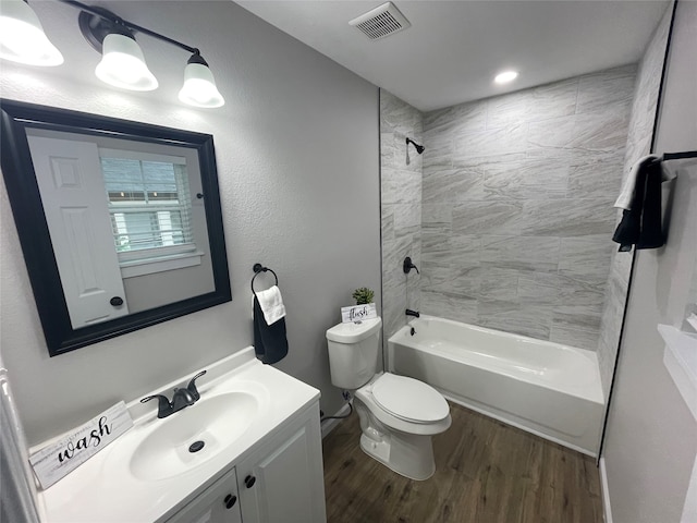 full bathroom featuring hardwood / wood-style floors, tiled shower / bath combo, vanity, and toilet