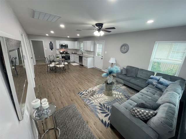 living room with wood-type flooring, sink, and ceiling fan