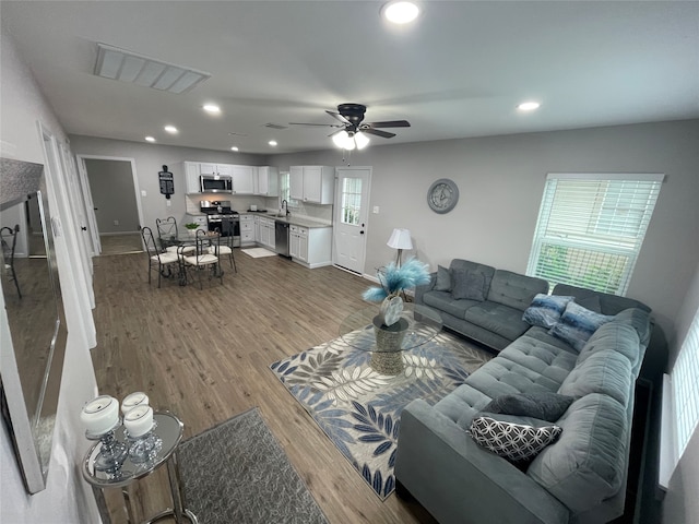 living room with wood-type flooring, sink, and ceiling fan