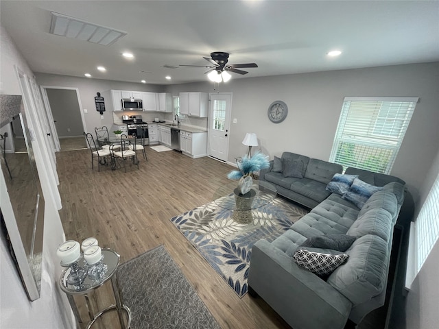 living room featuring ceiling fan, sink, and light hardwood / wood-style floors