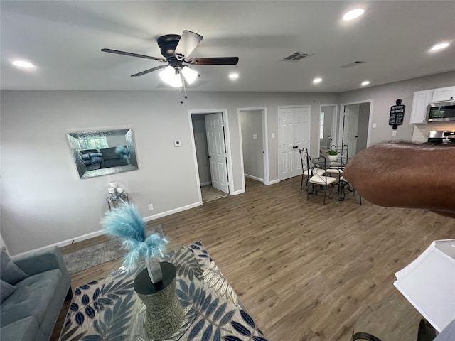 living room with ceiling fan and dark hardwood / wood-style flooring