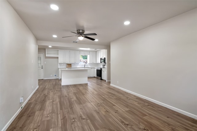 kitchen featuring light hardwood / wood-style floors, white cabinets, ceiling fan, sink, and electric range