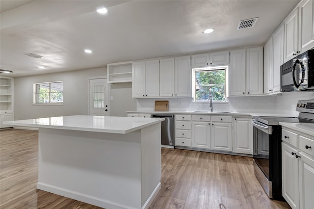 kitchen with appliances with stainless steel finishes, plenty of natural light, sink, and white cabinetry