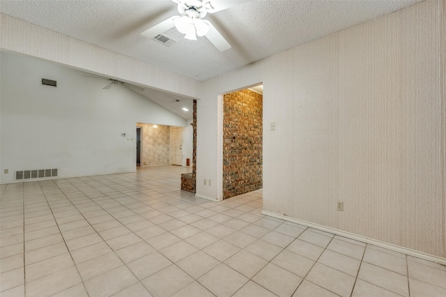 tiled spare room featuring ceiling fan, a textured ceiling, lofted ceiling, and brick wall