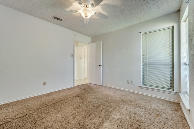 unfurnished room with a textured ceiling, ceiling fan, and light carpet