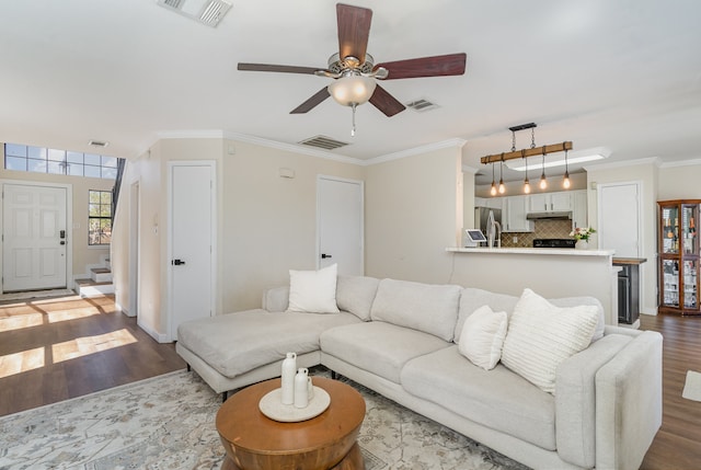 living room with ornamental molding, wood-type flooring, and ceiling fan