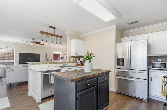 kitchen with wood counters, sink, white cabinets, a kitchen island, and stainless steel appliances