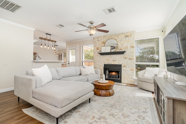 living room with wood-type flooring, ceiling fan, a fireplace, and crown molding