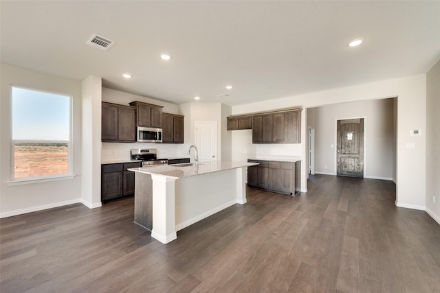 kitchen with sink, dark hardwood / wood-style flooring, stainless steel appliances, and an island with sink