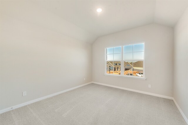 spare room with carpet floors and lofted ceiling