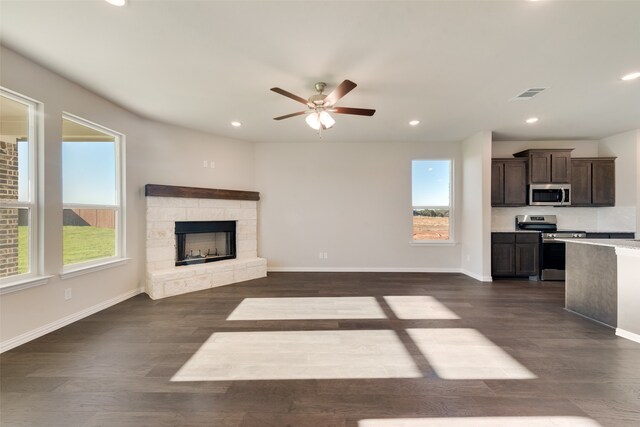 unfurnished living room featuring a fireplace, ceiling fan, and dark wood-type flooring