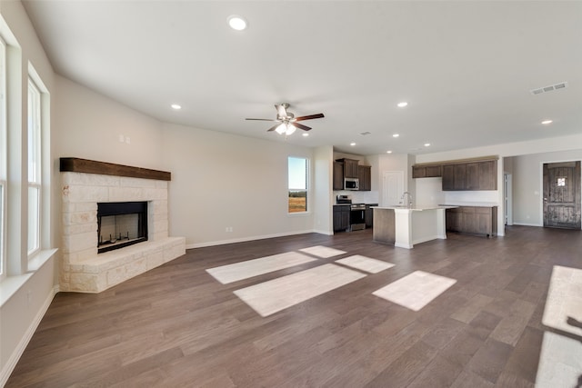 unfurnished living room featuring a fireplace, dark hardwood / wood-style floors, ceiling fan, and sink