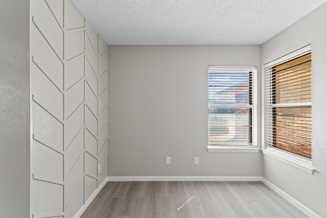 unfurnished room with a textured ceiling and light hardwood / wood-style floors