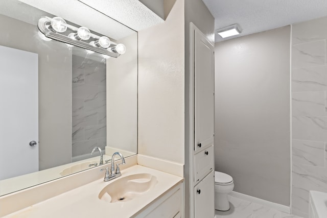 bathroom with a textured ceiling, a tub to relax in, vanity, and toilet