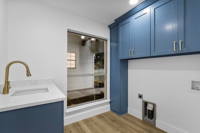 washroom featuring light wood-type flooring, hookup for a washing machine, hookup for an electric dryer, sink, and cabinets