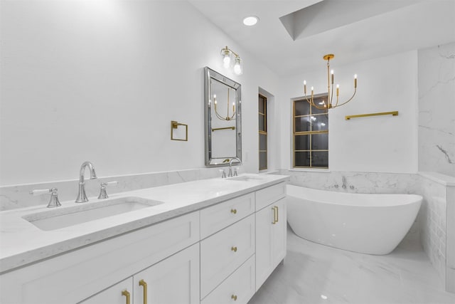 bathroom with an inviting chandelier, vanity, a bathing tub, and tile walls