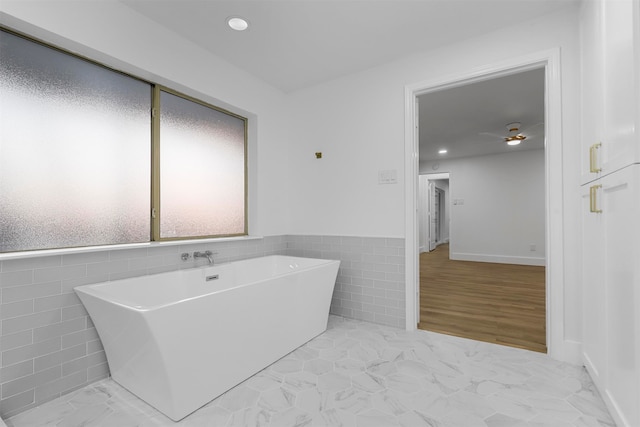 bathroom featuring tile walls, a tub, and hardwood / wood-style flooring