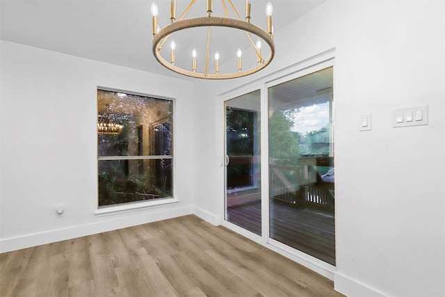 unfurnished dining area with wood-type flooring and a chandelier