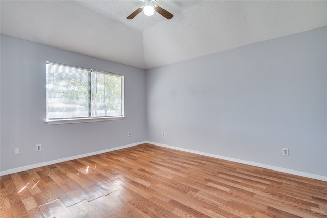 empty room with a textured ceiling, vaulted ceiling, ceiling fan, and light hardwood / wood-style flooring