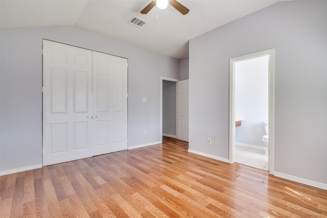 unfurnished bedroom with light wood-type flooring, vaulted ceiling, ceiling fan, and a closet