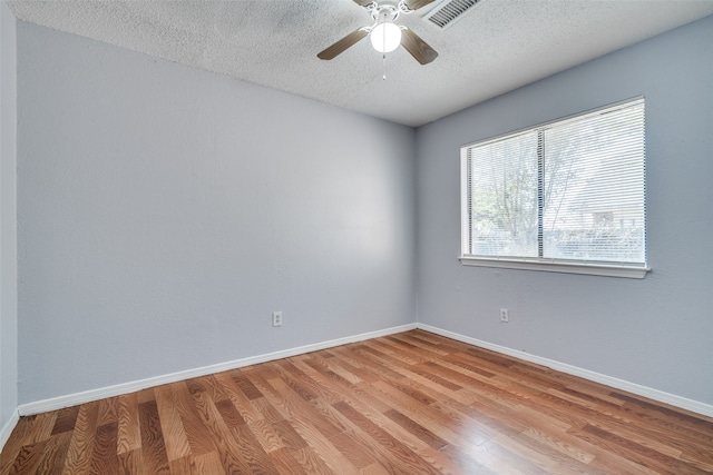 unfurnished room with ceiling fan, a textured ceiling, and light wood-type flooring