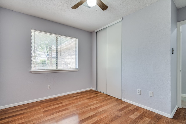 unfurnished bedroom with a textured ceiling, ceiling fan, a closet, and light hardwood / wood-style flooring