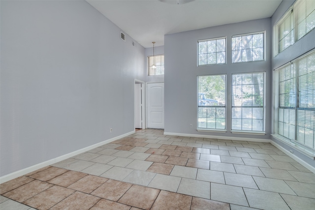 tiled spare room with a towering ceiling