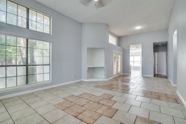 interior space featuring a towering ceiling, ceiling fan, and plenty of natural light