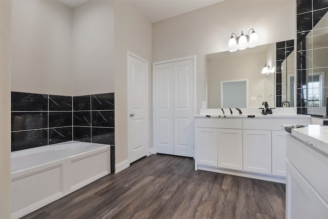 bathroom with a washtub, vanity, and wood-type flooring