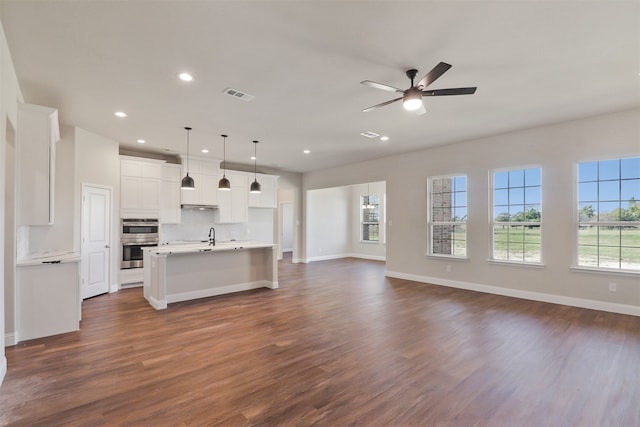 unfurnished living room featuring ceiling fan and dark wood-type flooring