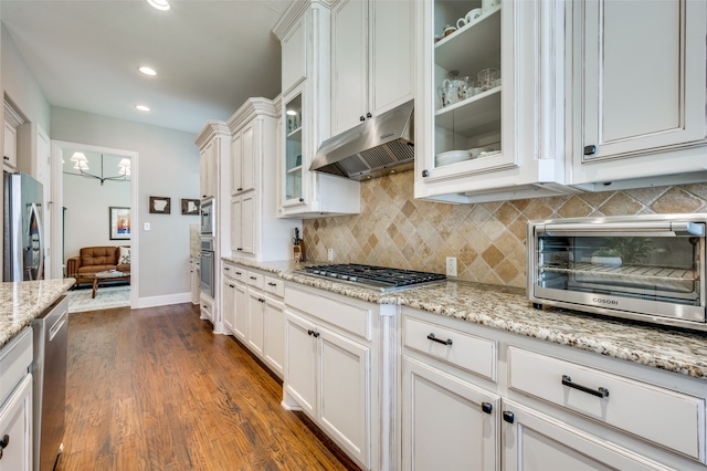 kitchen with light stone countertops, stainless steel appliances, tasteful backsplash, dark wood-type flooring, and white cabinetry