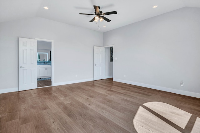 unfurnished bedroom featuring connected bathroom, lofted ceiling, ceiling fan, and hardwood / wood-style flooring