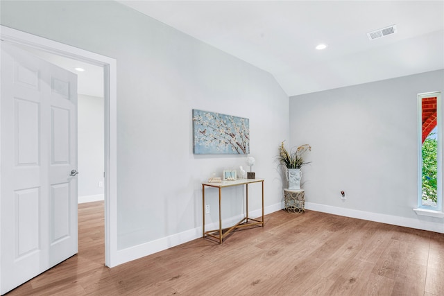 spare room featuring light wood-type flooring and lofted ceiling