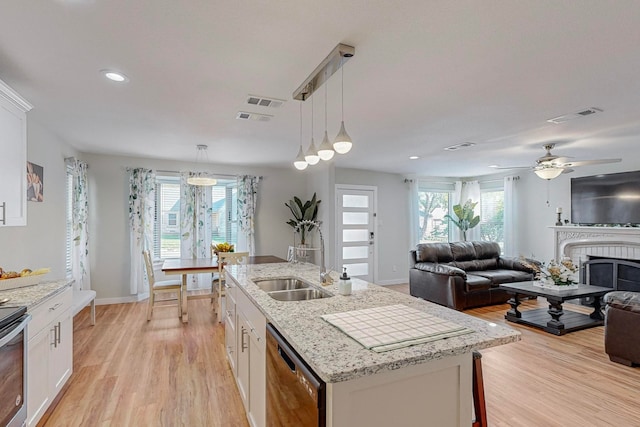 kitchen featuring pendant lighting, light hardwood / wood-style flooring, a kitchen island with sink, white cabinetry, and dishwasher