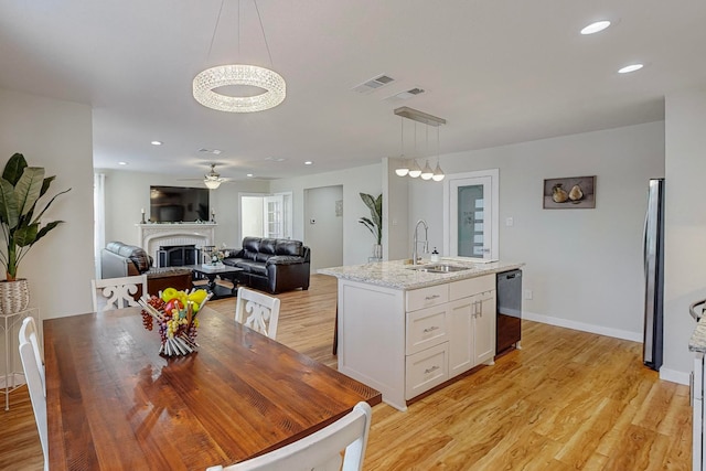 interior space with ceiling fan with notable chandelier, light wood-type flooring, and sink