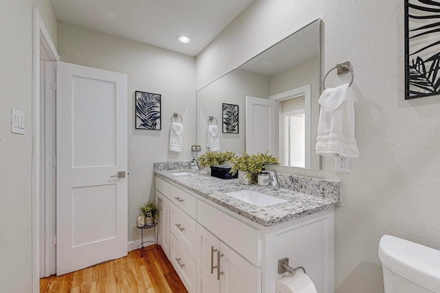 bathroom with hardwood / wood-style floors, vanity, and toilet