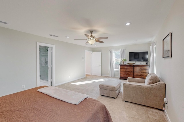 bedroom with ceiling fan, ensuite bath, and light carpet