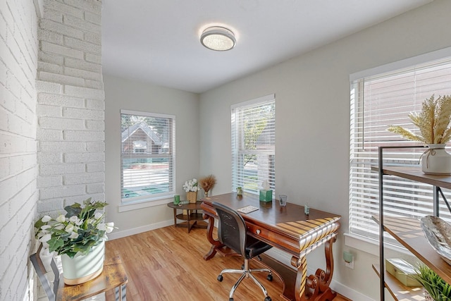 home office with brick wall and light wood-type flooring