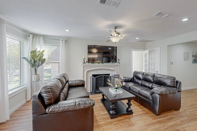 living room featuring ceiling fan, light hardwood / wood-style floors, and a fireplace