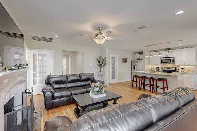 living room featuring ceiling fan, light hardwood / wood-style flooring, and sink