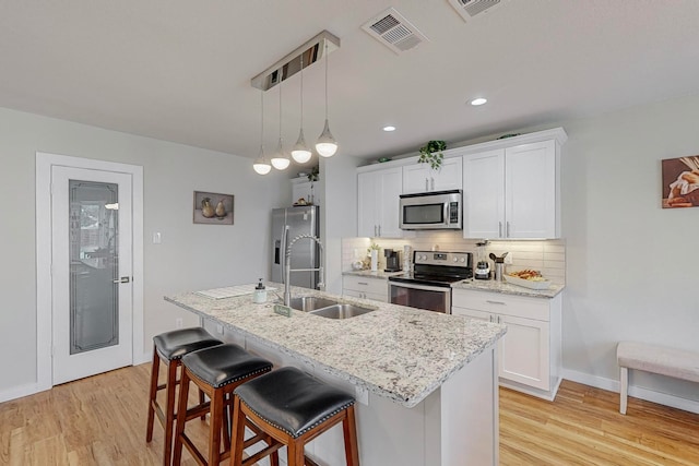 kitchen with white cabinetry, light hardwood / wood-style floors, appliances with stainless steel finishes, and sink