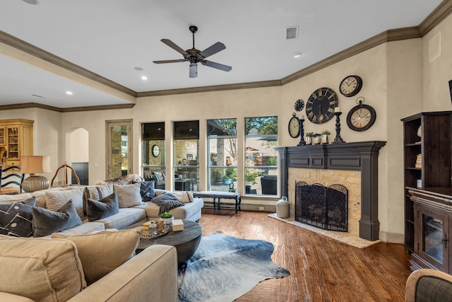 living room with ornamental molding, a wealth of natural light, a stone fireplace, and dark hardwood / wood-style flooring